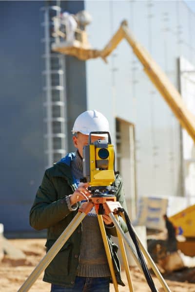 Surveyor using total station equipment to verify boundaries for alta land title survey accuracy