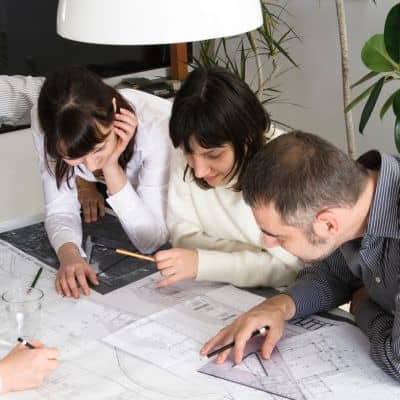 A project team reviewing blueprints and site plans to verify details for a property survey during early construction planning