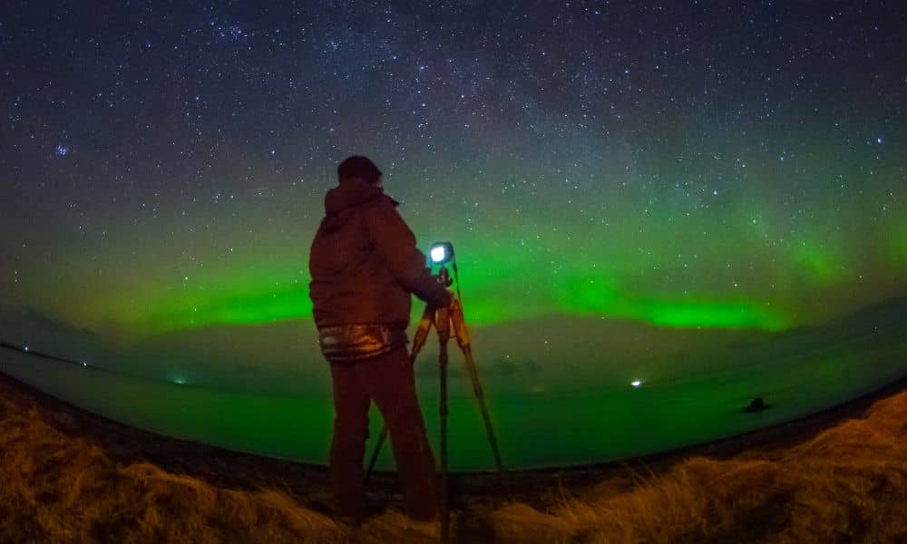 Surveyor using GPS equipment for a boundary line survey under the aurora borealis during a solar storm.

