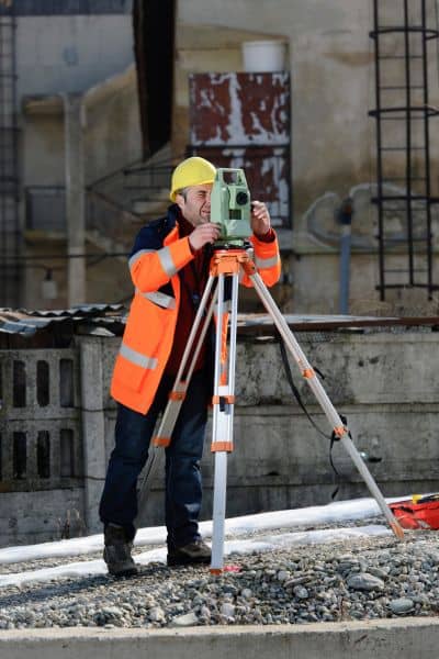 Land surveyor using equipment to perform a due diligence survey and identify site risks
