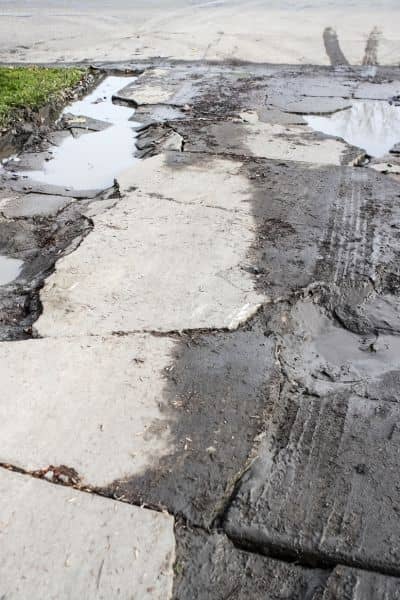 Damaged driveway with water pooling after heavy rain showing need for a flood elevation survey before building permits
