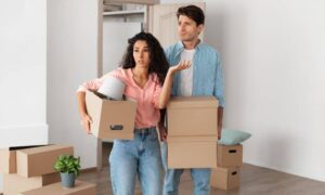 property line survey confused homeowners - ALTA SURVEY Minneapolis Confused young couple holding moving boxes, unsure about property line survey and unexpected offers to buy their land