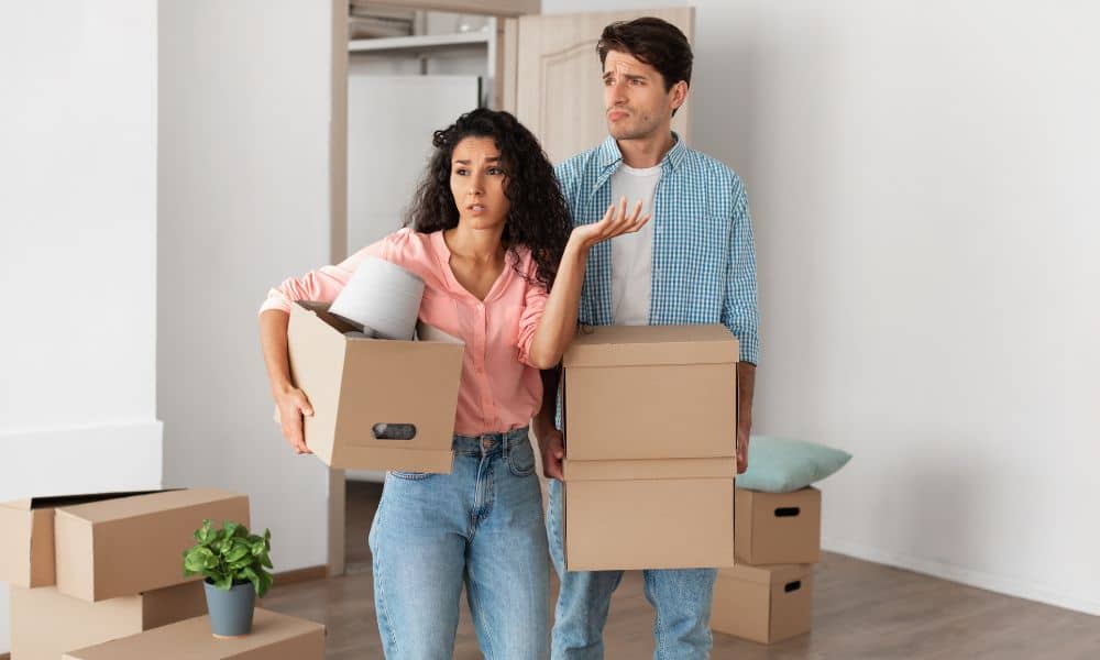 property line survey confused homeowners - ALTA SURVEY Minneapolis onfused young couple holding moving boxes, unsure about property line survey and unexpected offers to buy their land