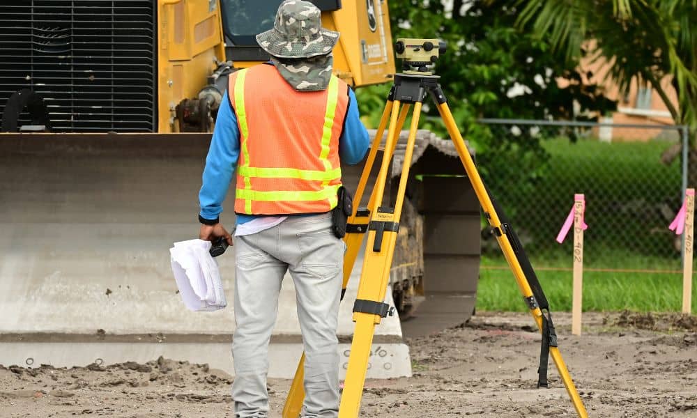 Property boundary field measurement surveyor - ALTA SURVEY Minneapolis Surveyor performing a lot survey to verify residential property boundary lines near a construction area