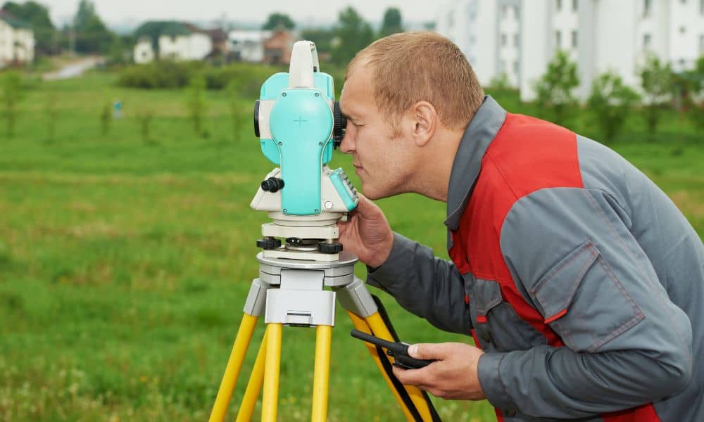 Surveyor measuring boundary with total station - ALTA SURVEY Minneapolis Local surveyor measuring a residential property line with a total station