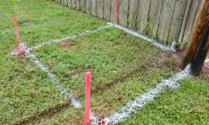 Backyard with boundary stakes marking the property line survey area for garage planning