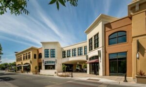 Street view of a mixed-use commercial property with storefronts, sidewalks, and pedestrian access