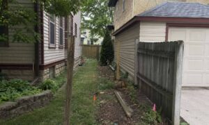Property survey for fence installation showing survey markers along a shared lot line between neighboring homes in Minneapolis