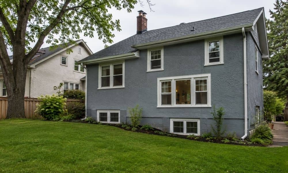 Home with basement windows and a sloped yard, where an elevation certificate may be needed before remodeling